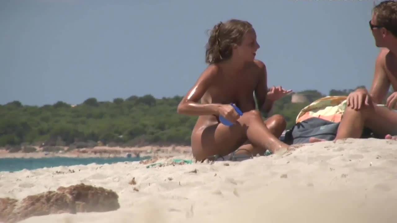 Un voyeur filme une jeune femme avec des gros seins sur la plage